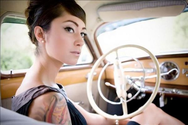 Classy and sexy brunette woman with tattoos in an old car